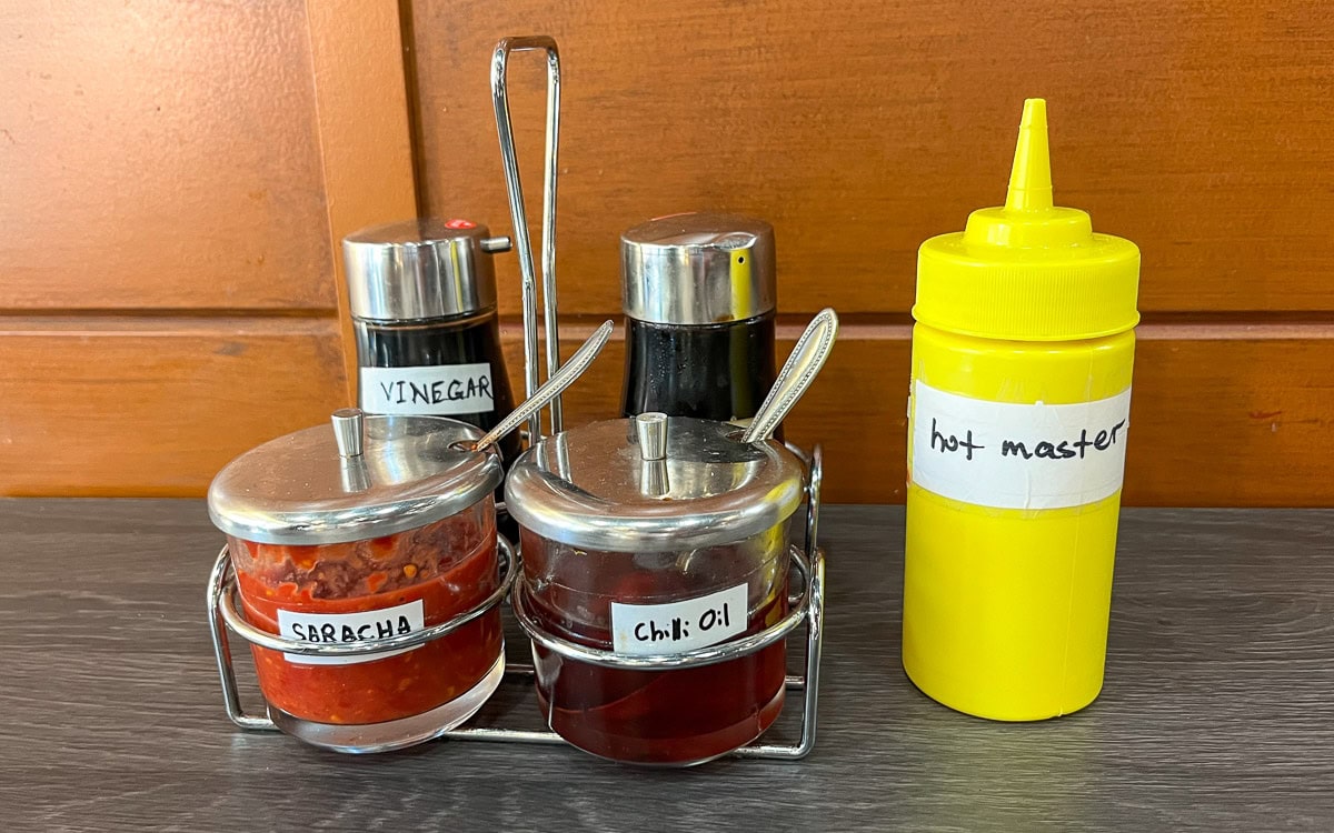 Assortment of condiments including chili oil, sriracha, and hot mustard